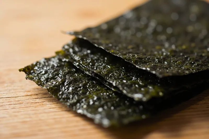 Stack of dried nori seaweed sheets on a wooden table