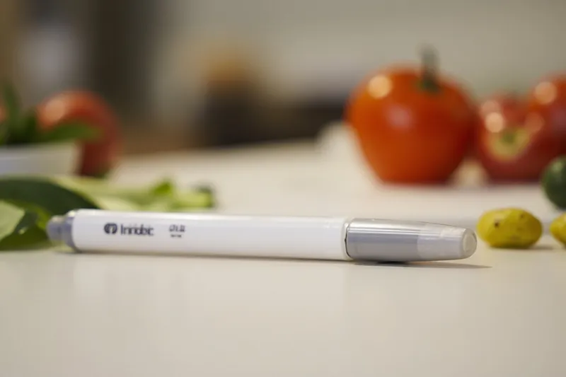 Insulin pen lying on a kitchen table beside a glucose meter