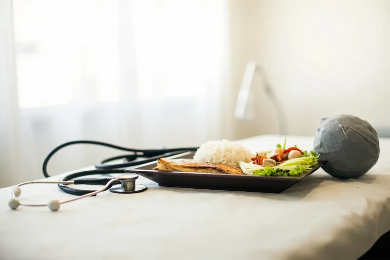 Stethoscope next to Japanese fish and rice meal on clinic examination table