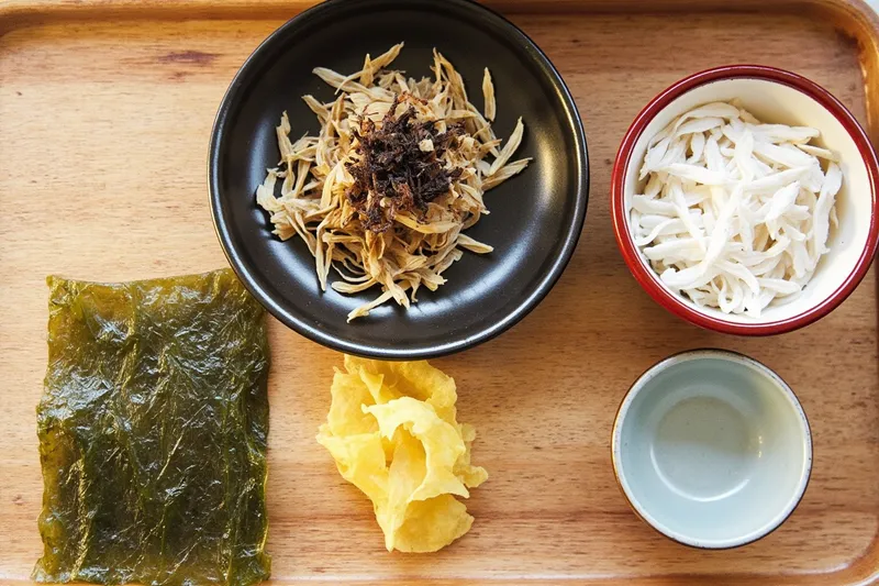 A dried kombu strip and flakes of katsuobushi laid out on a board for making dashi.