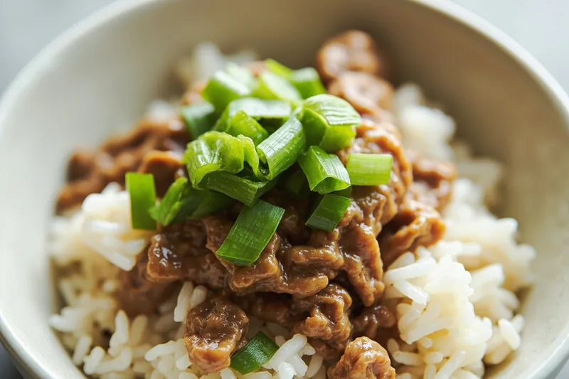 Close-up of fermented soybean natto with green scallion on steamed white rice.