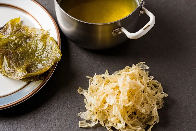 Dried kelp and bonito flakes beside a pot of homemade dashi broth.