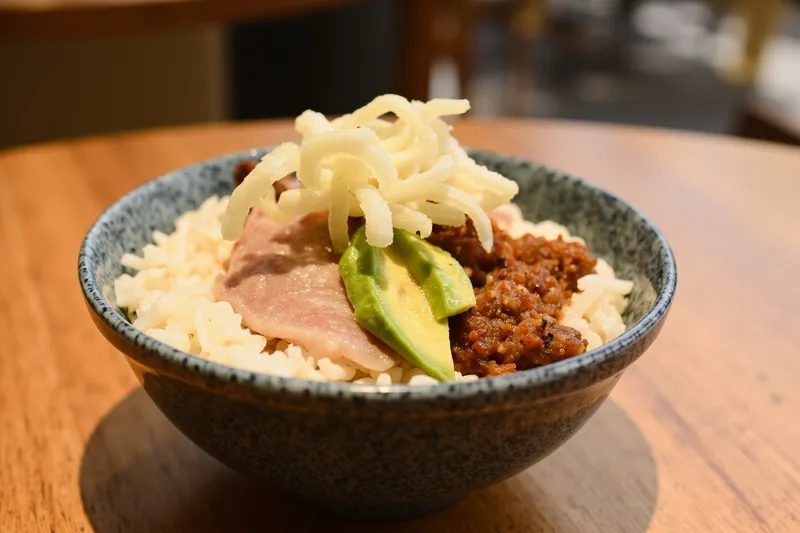 Rice bowl filled with topped rice, tuna slices, avocado and grated yam