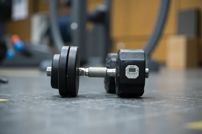 Two rubber-coated dumbbells lying on the floor of a gym
